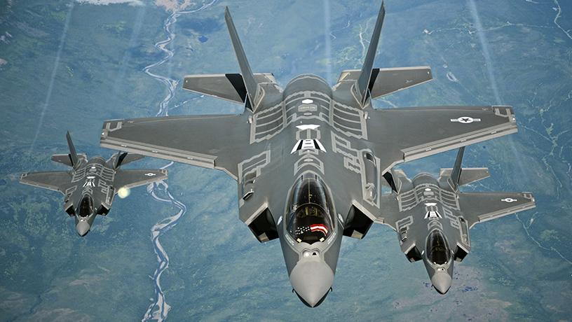 Three F-35A aircraft flying over a river.