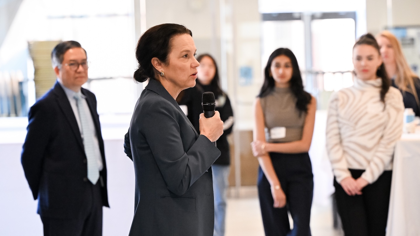 A woman holding a microphone addresses a crowded room