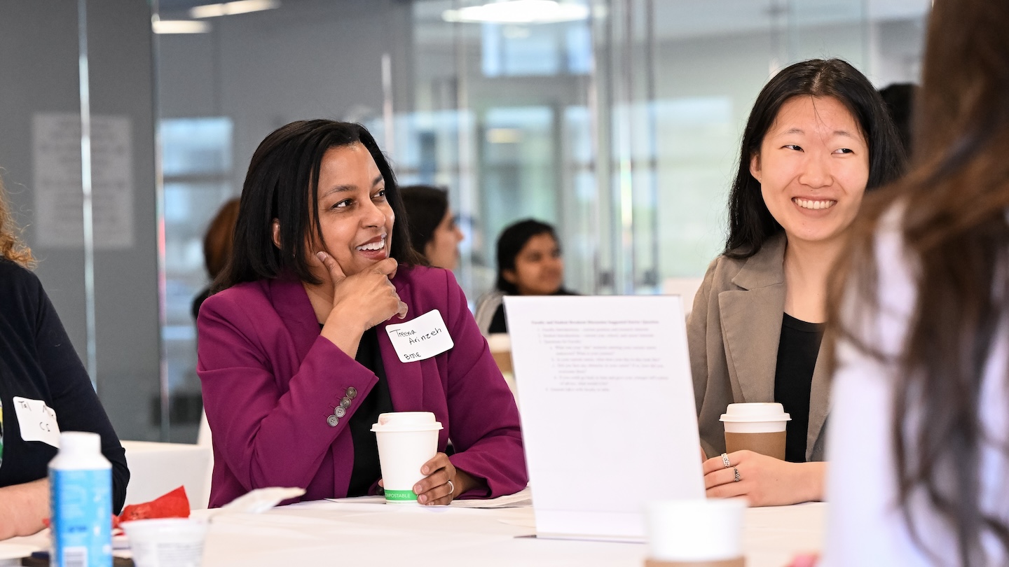 Women wearing name tags conversing at a table