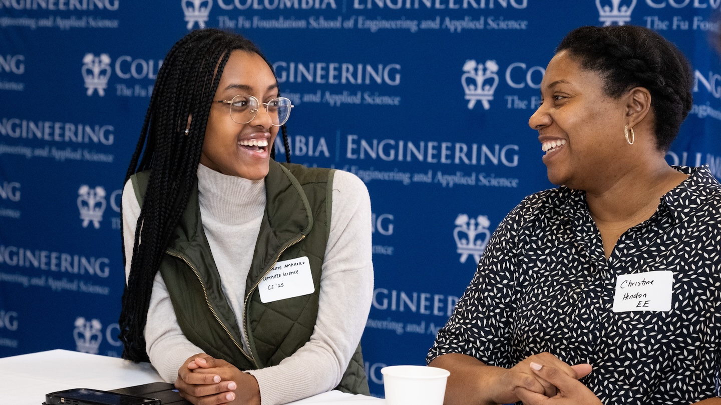 Two women conversing in front of a Columbia Engineering backdrop