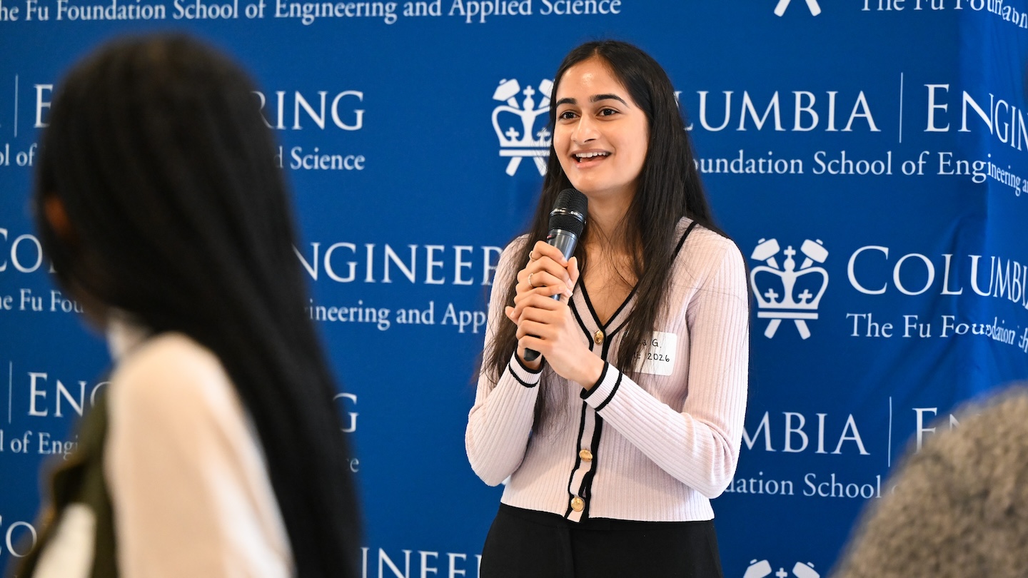 A women holding a microphone in front of a Columbia Engineering backdrop