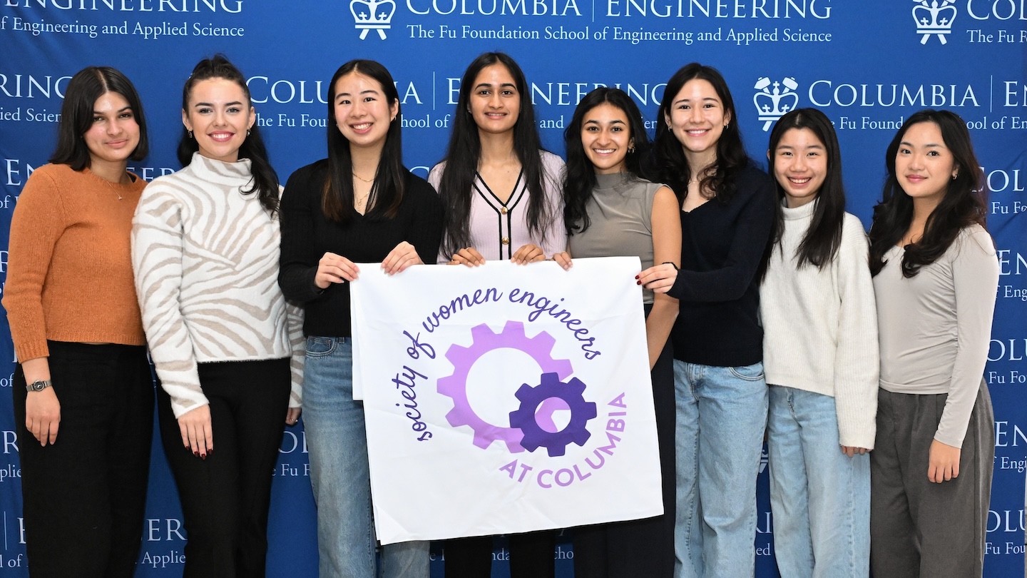 Eight women pose for a photo holding a sign that reads "Society of women engineers at Columbia"